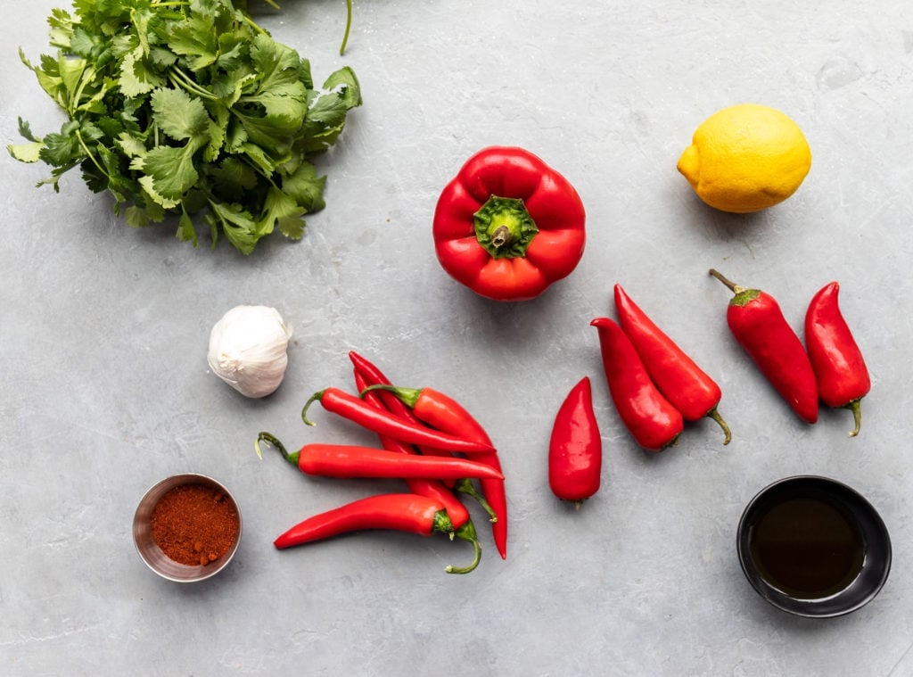 bbq peri peri chicken sauce ingredients: red bell pepper, red serrano, red jalapenos, garlic cloves, blackening seasoning, fresh herbs, lemon juice, and vegetable oil