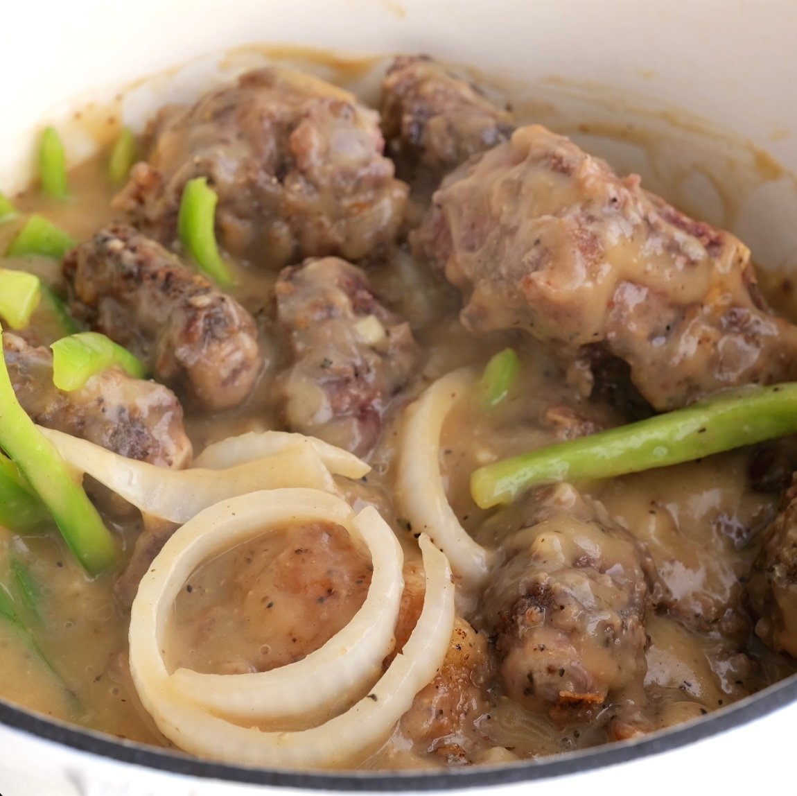 Browned oxtails in gravy with onion and bell pepper.