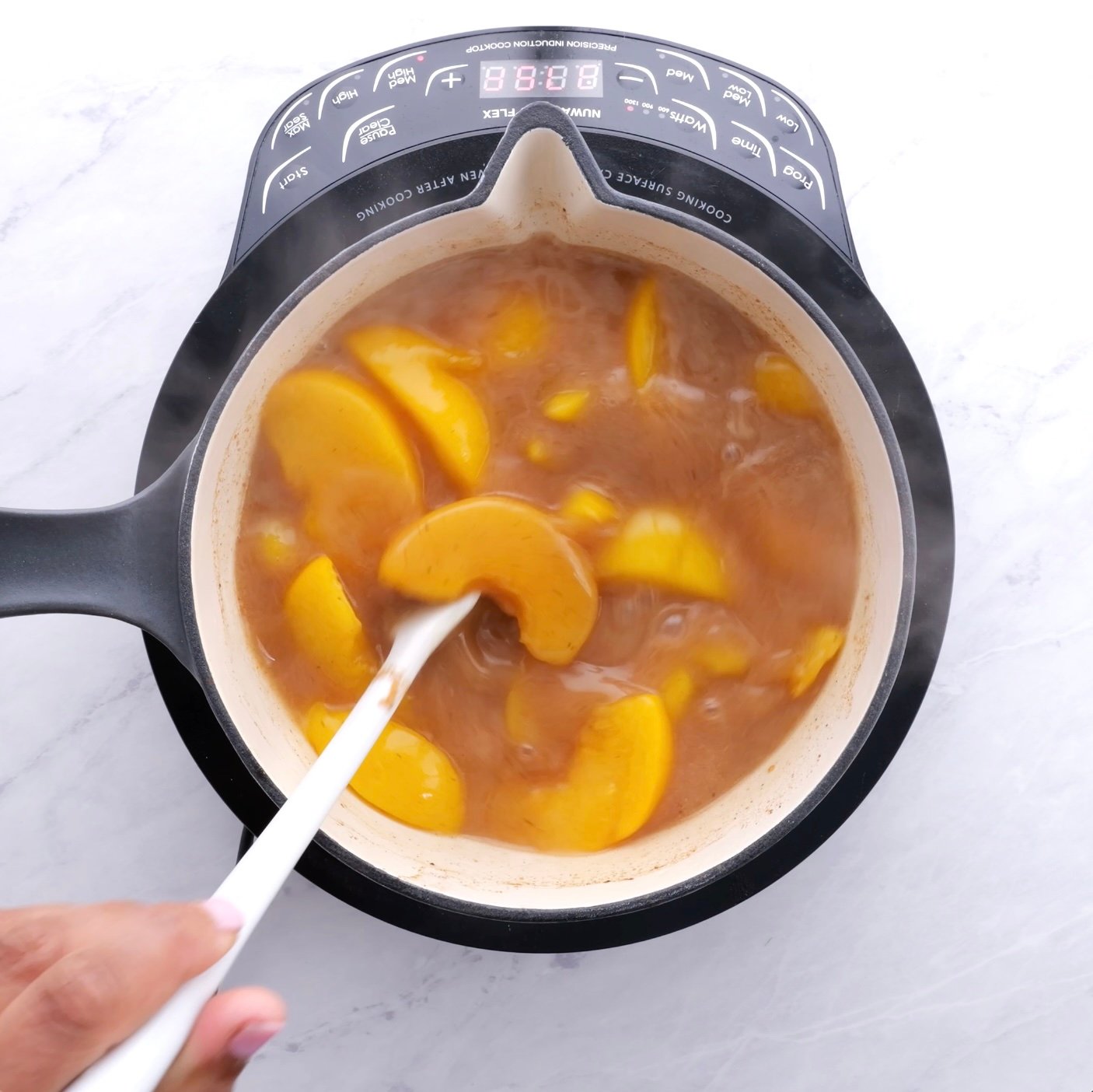 Peach cobbler filling cooking in a pot.