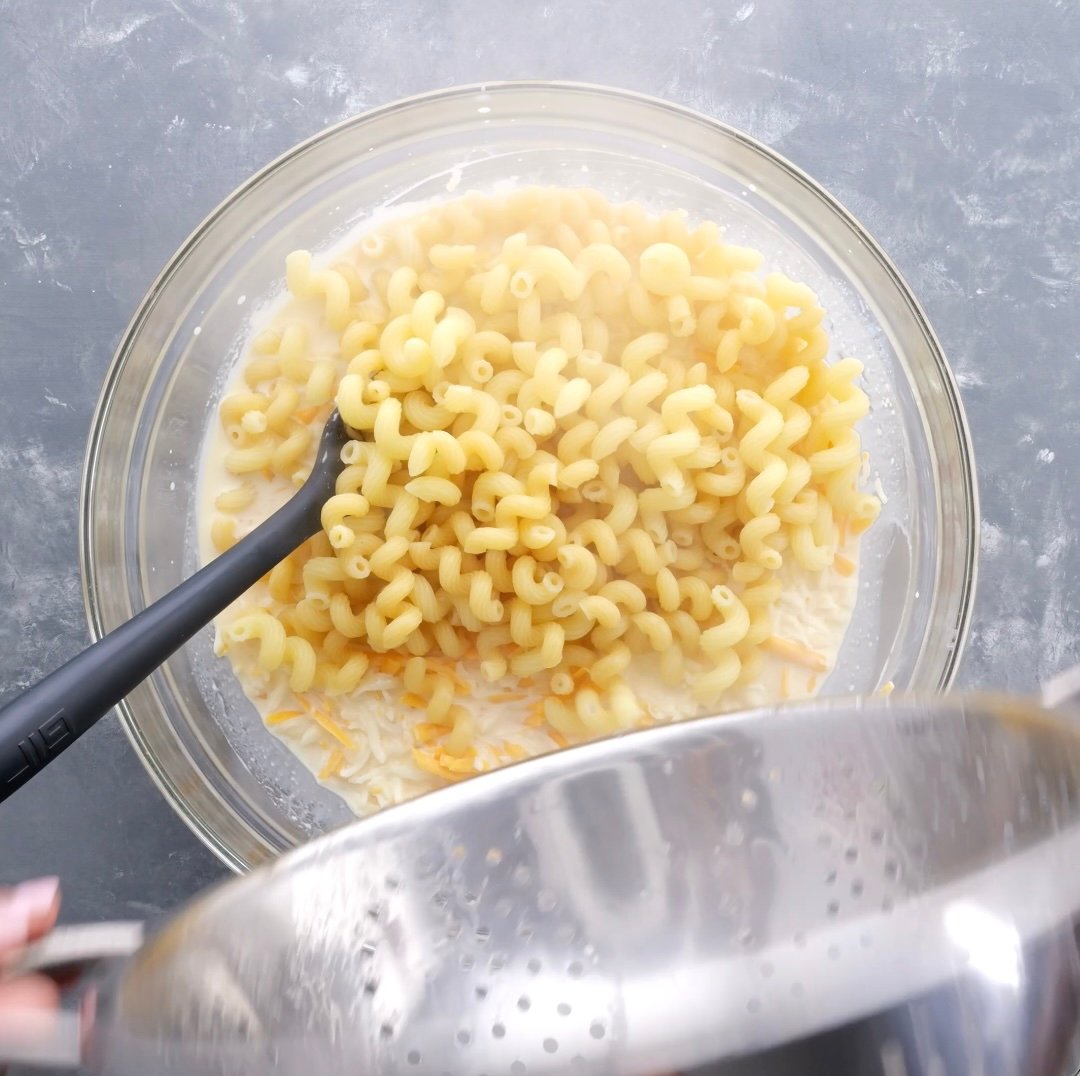 Cooked macaroni in a bowl of cheese and milk.