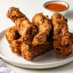 fried ribs on a plate with a side of hot sauce