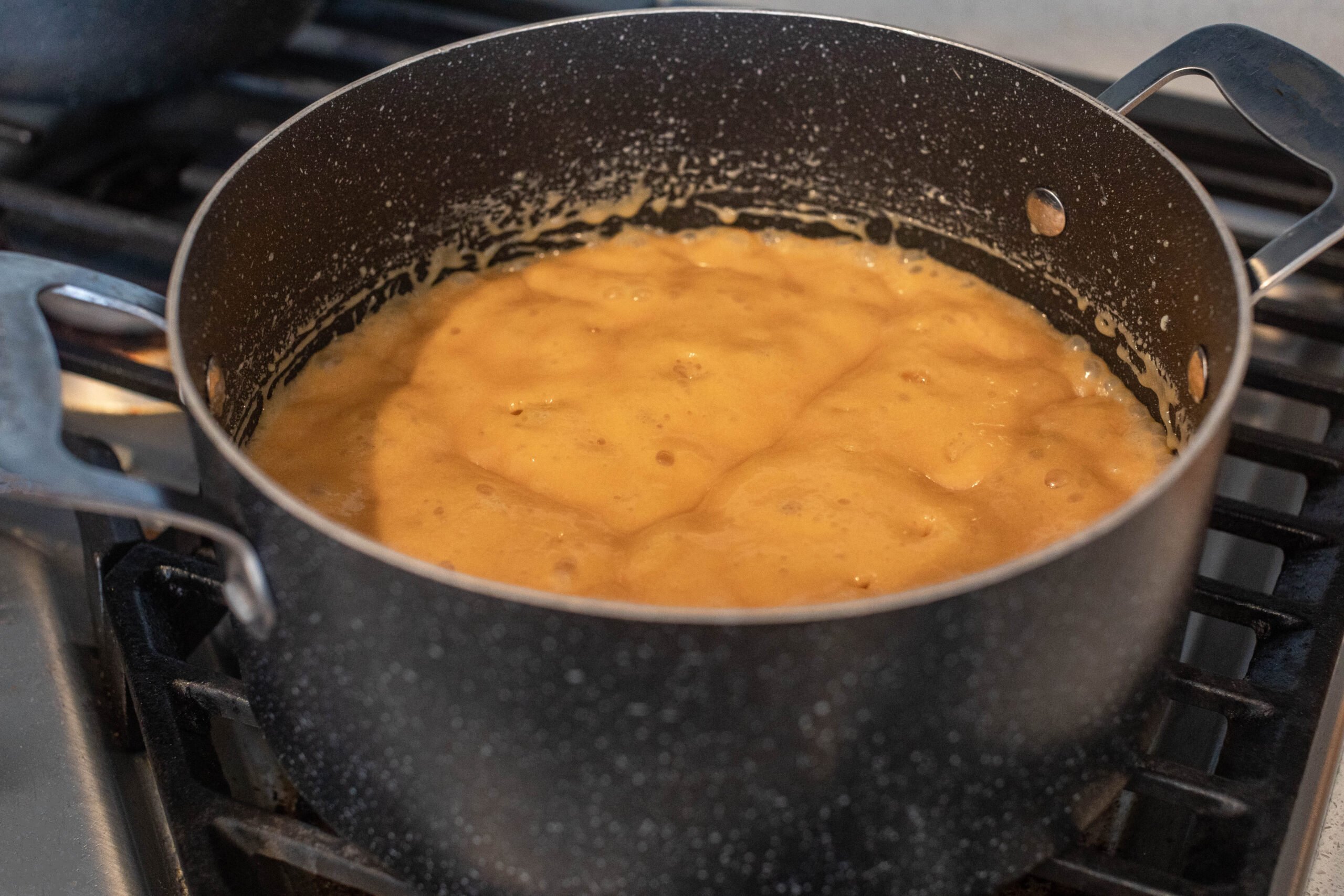 a saucepan on the stove with caramel for caramel cake
