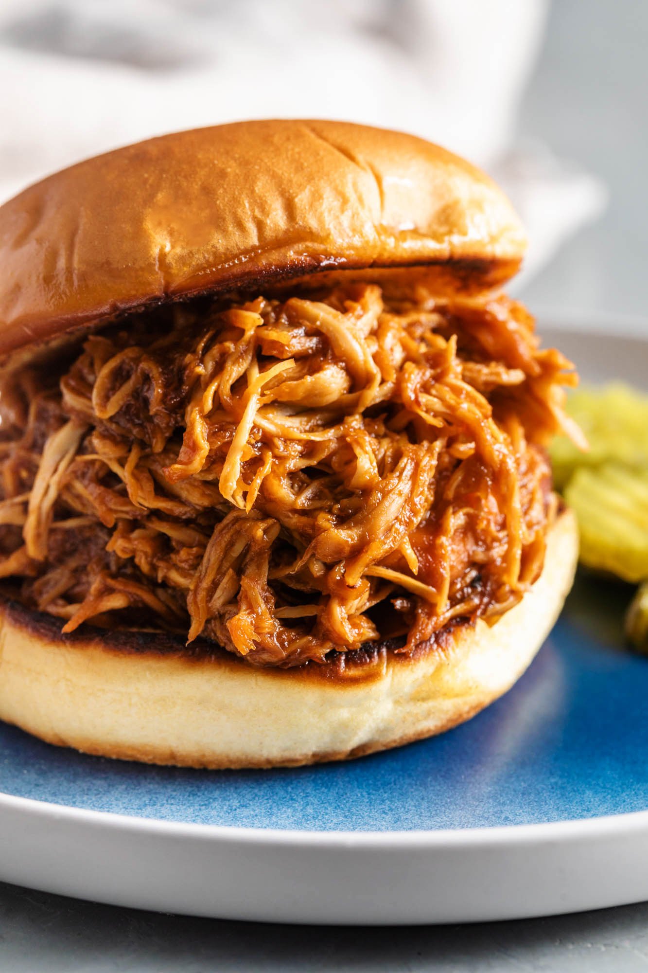 bbq pulled chicken sandwich on a blue plate with a toasted bun