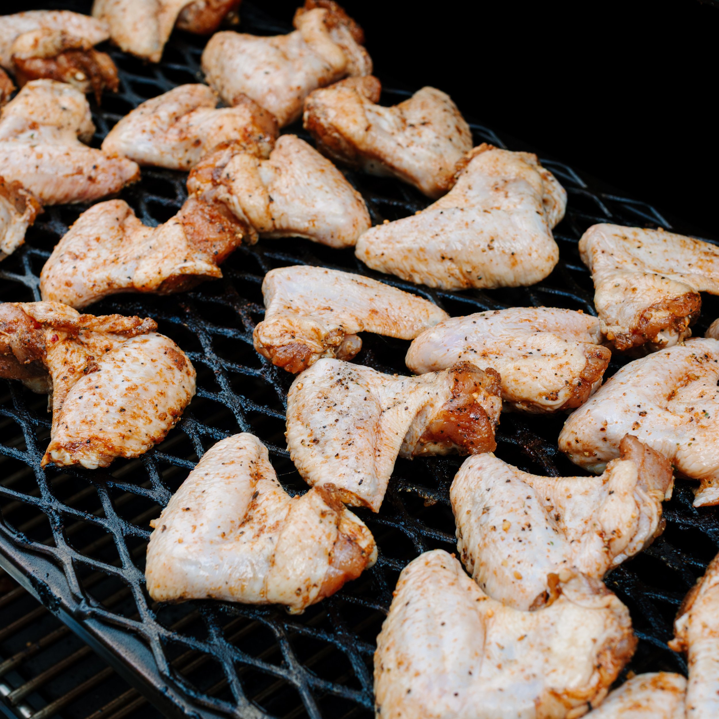 Raw chicken wings on a smoker.