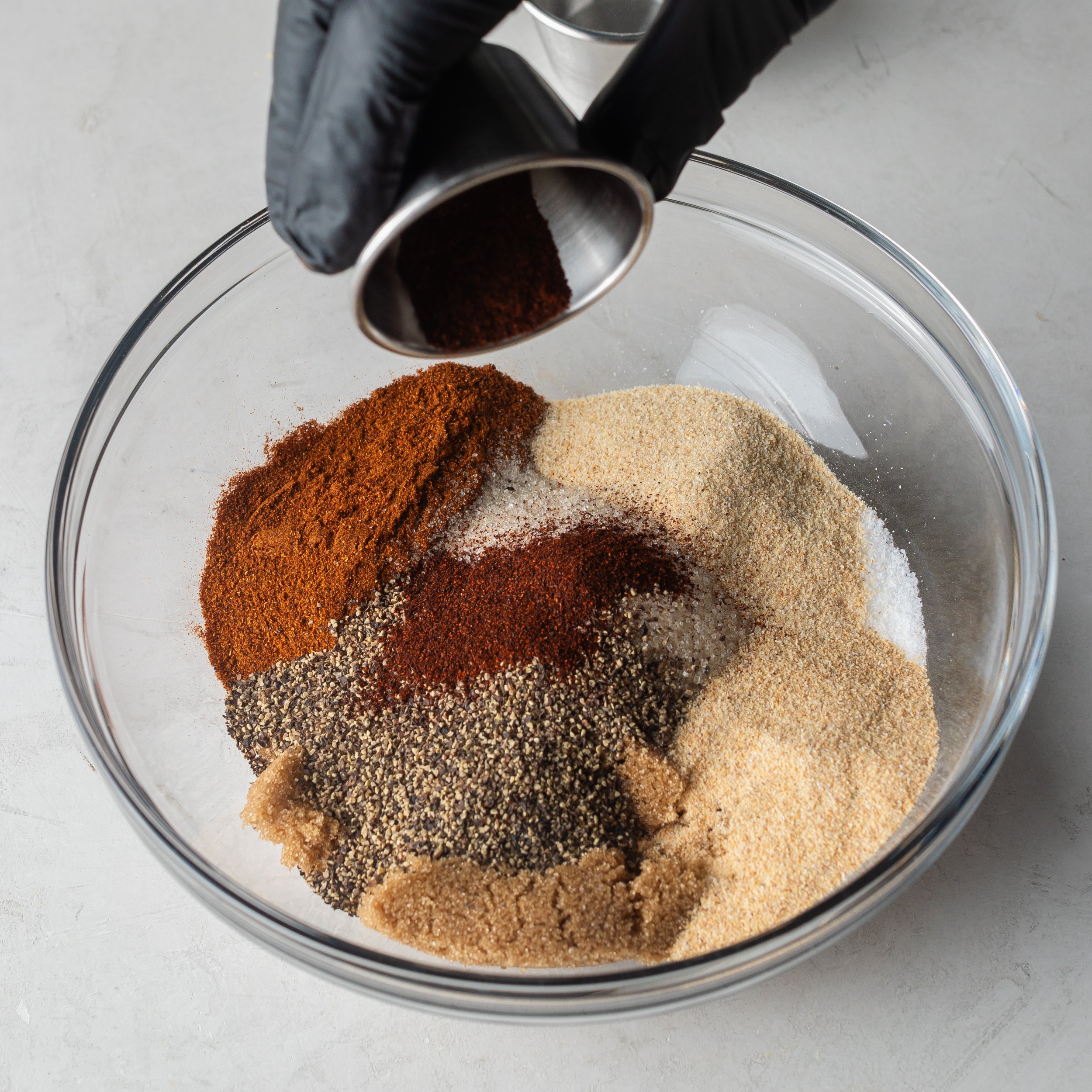 BBQ seasoning ingredients in a large glass mixing bowl.
