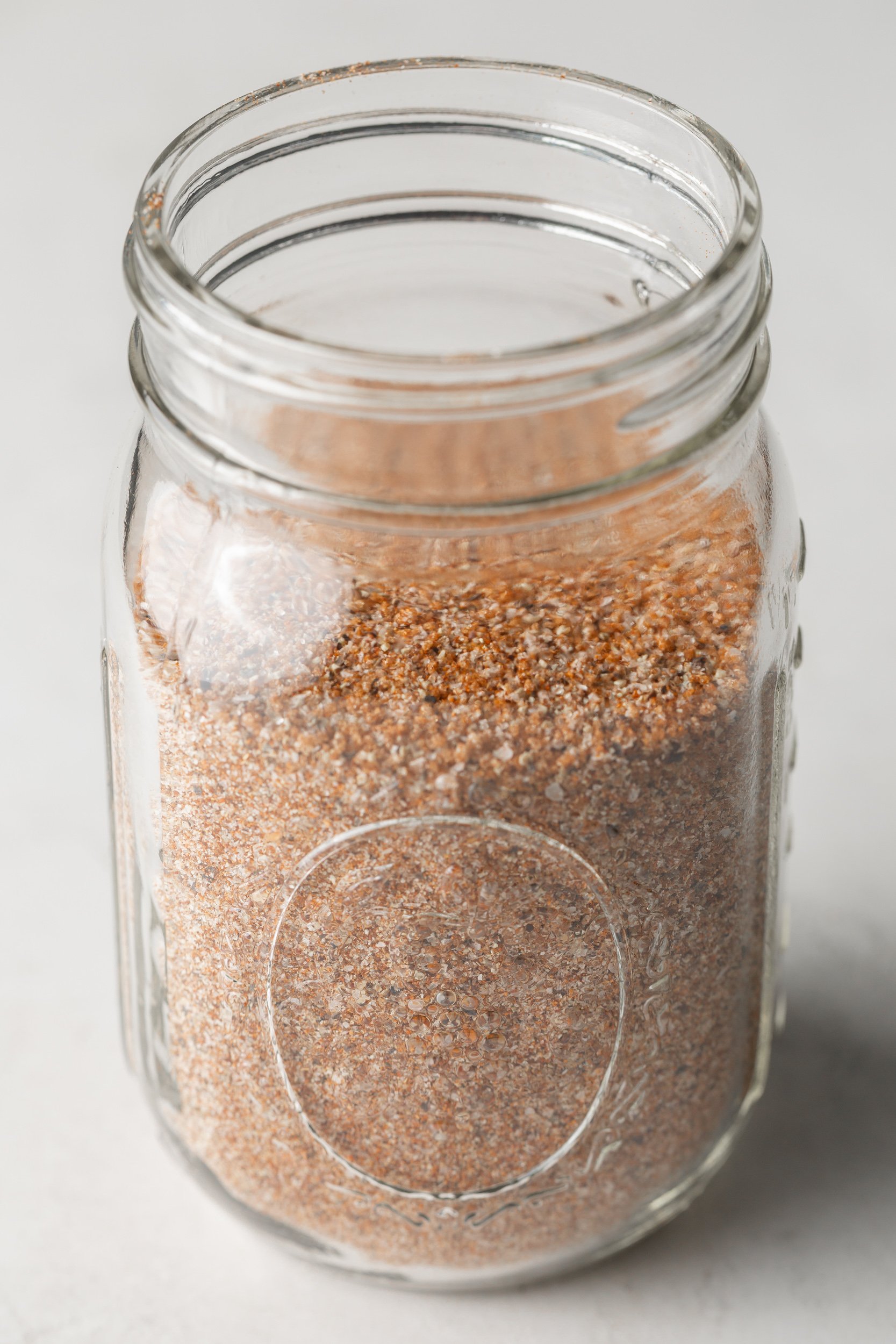 A closeup of BBQ seasoning in a glass mason jar.