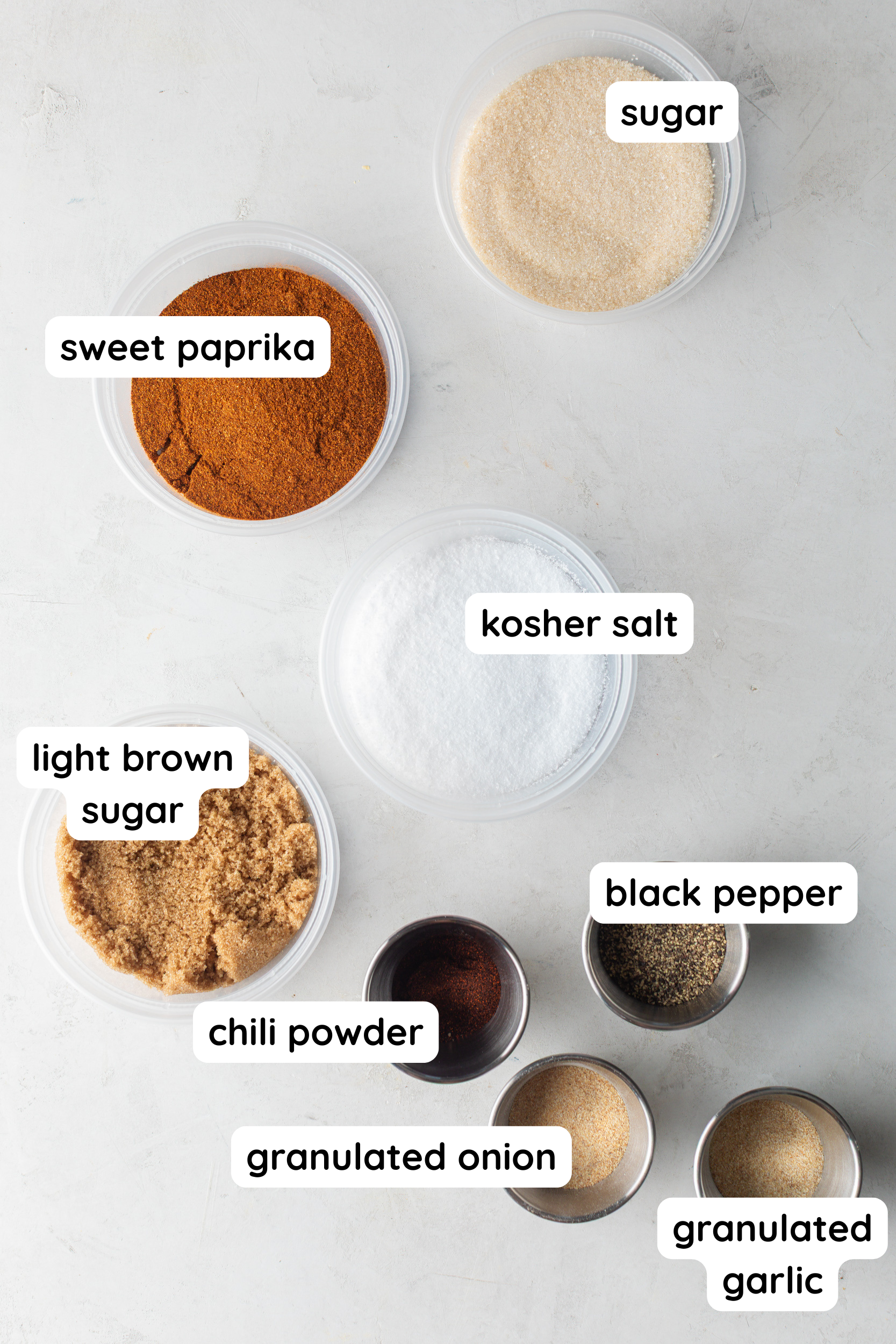 Homemade BBQ seasoning ingredients: paprika, sugar, salt, light brown sugar, black pepper, chili powder, granulated onion, granulated garlic.