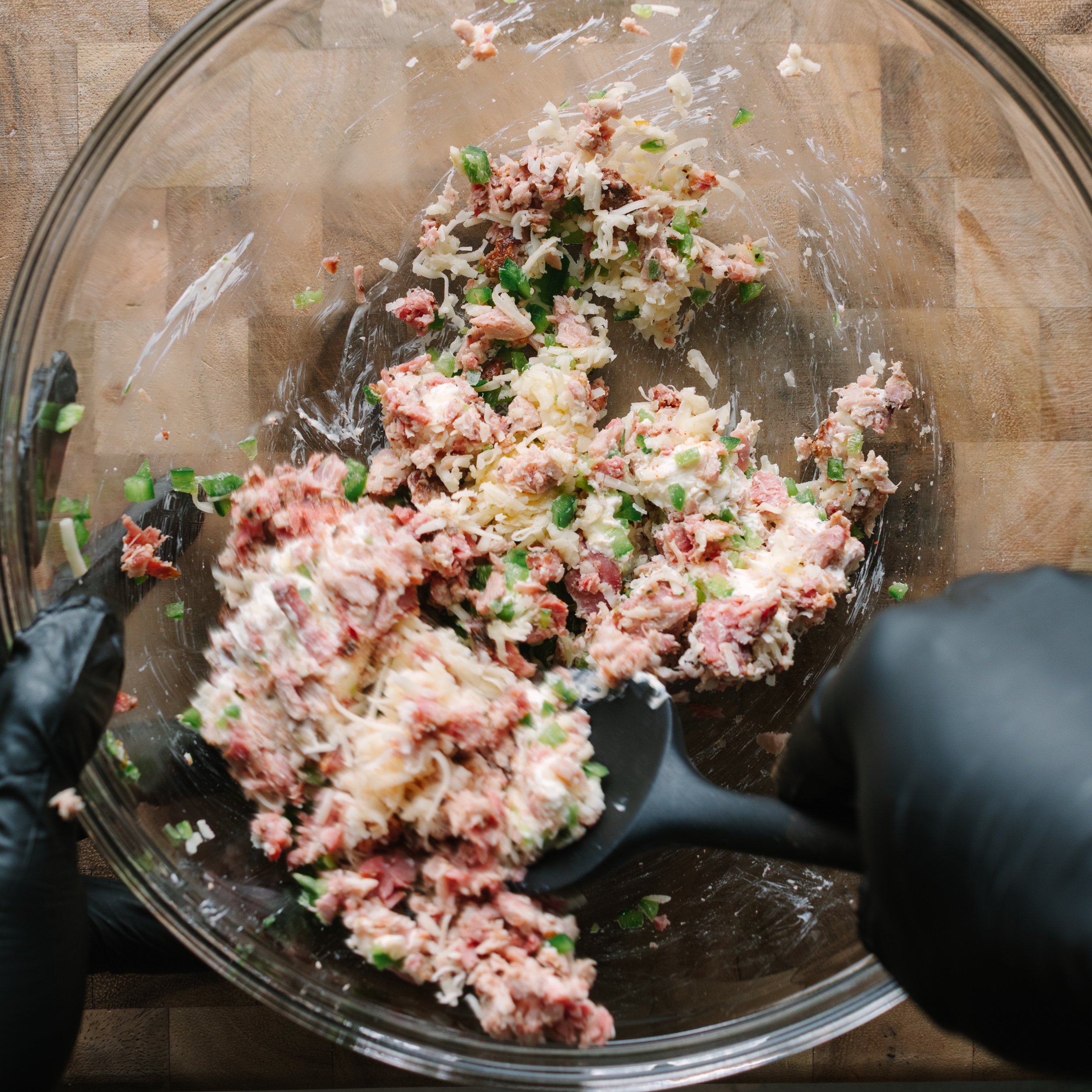 A clear mixing bowl with shotgun shell filling of pulled pork, cream cheese, and jalapeno.
