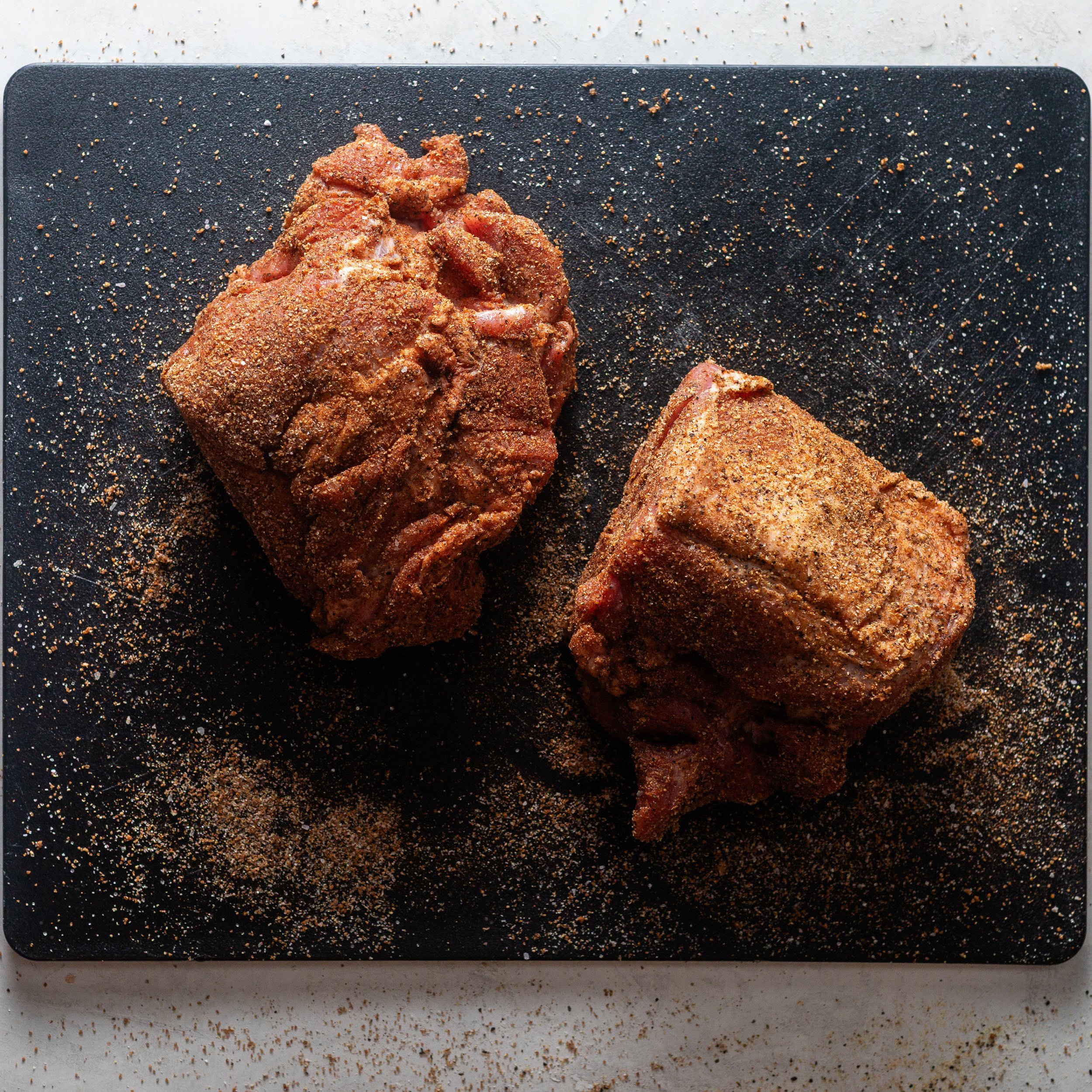 boneless pork shoulder seasoned on a black cutting board