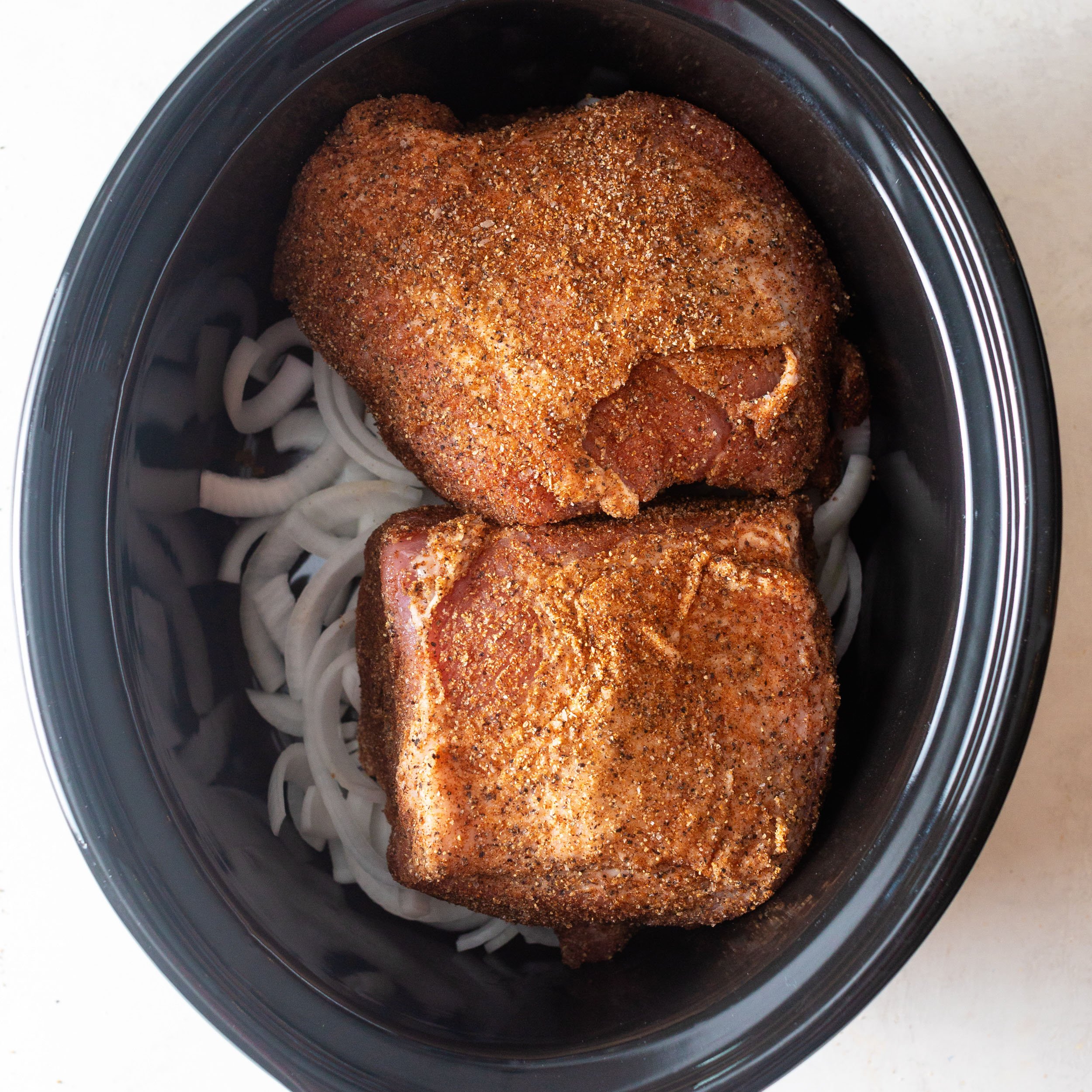 boneless pork shoulder in a slow cooker with white onions