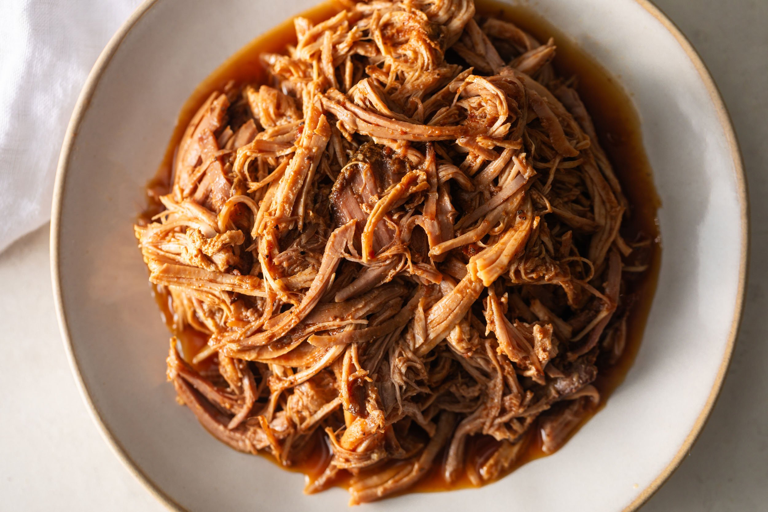 slow cooker BBQ pulled pork in a white shallow bowl